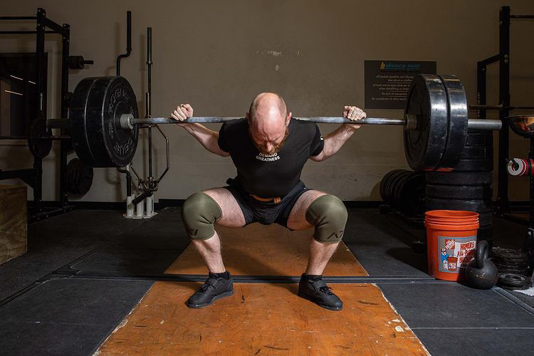 man doing a squat with a barbell