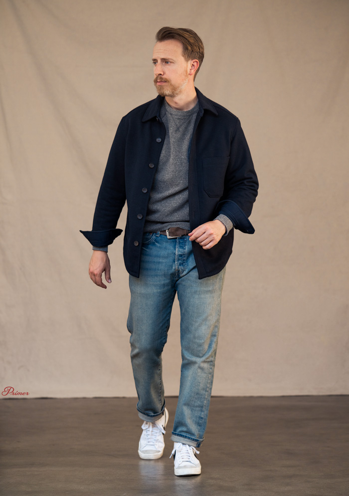 a man wearing an outfit made of a navy overcoat, grey sweatshirt, levi's 501 jeans, and white Nike Blazer hightop sneakers