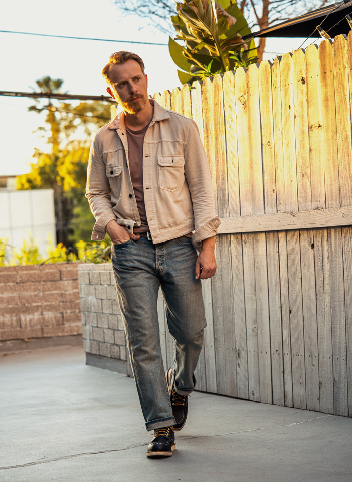 man wearing light wash levi's 501 jeans with a trucker jacket and boots