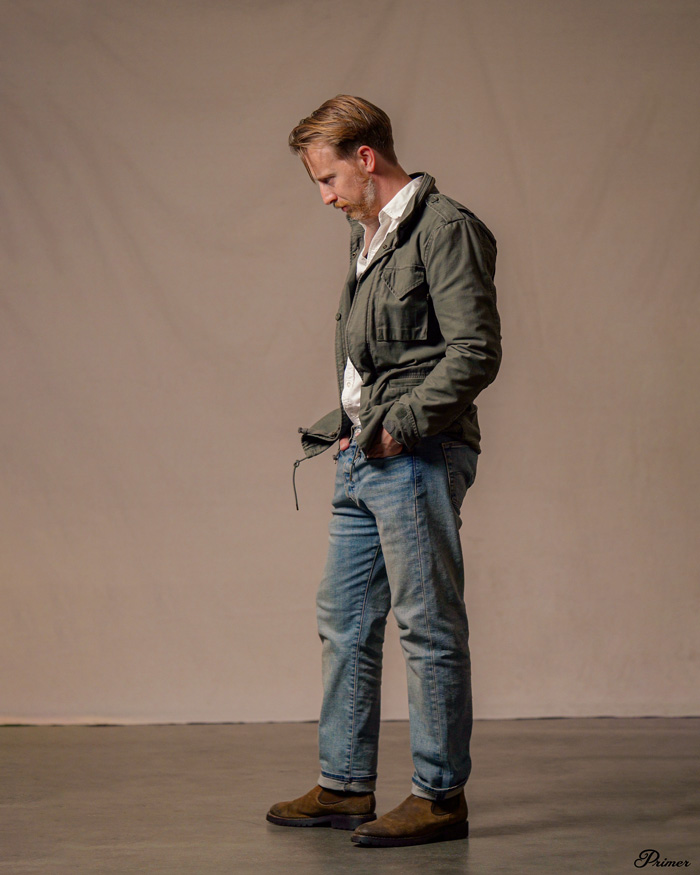 a man wearing a field jacket with denim jeans and boots
