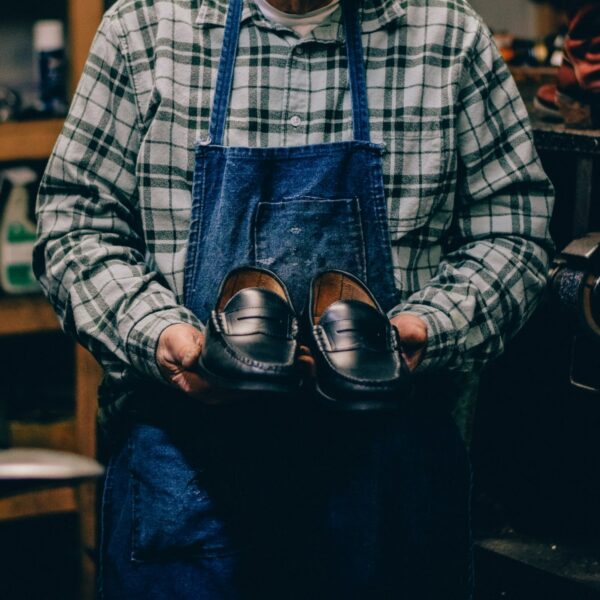 image of a person holding a pair of black leather loafer shoes