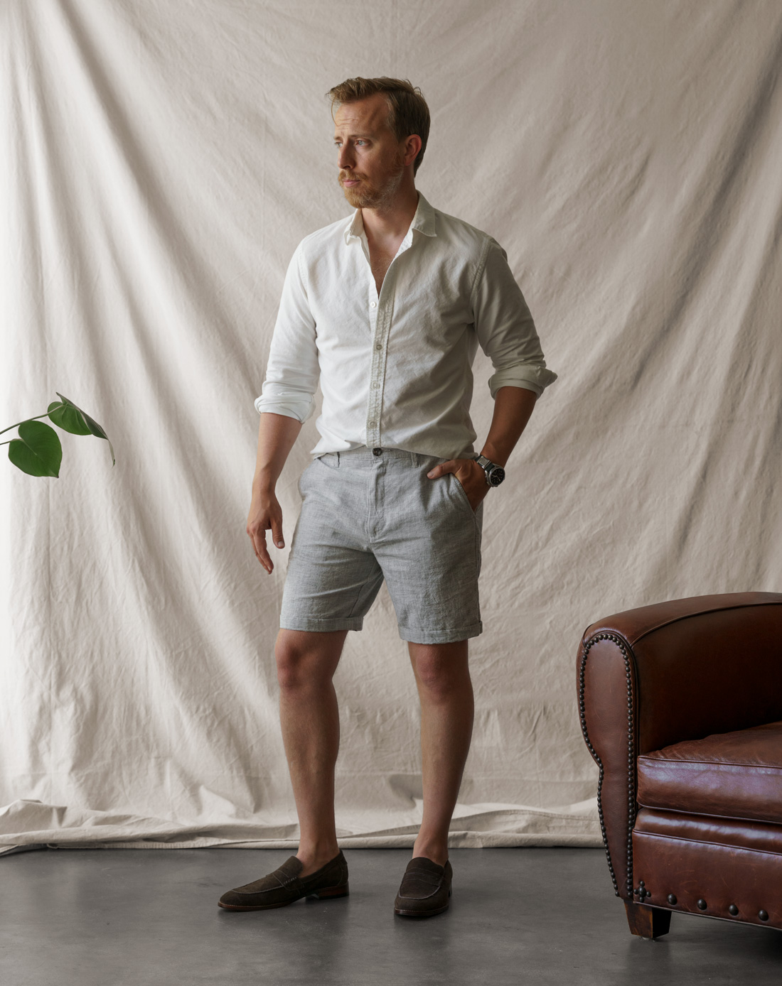 man wearing white oxford shirt with gray linen shorts and brown suede loafers for summer
