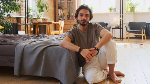 image of a man sitting on the floor wearing a brown shirt and white pants