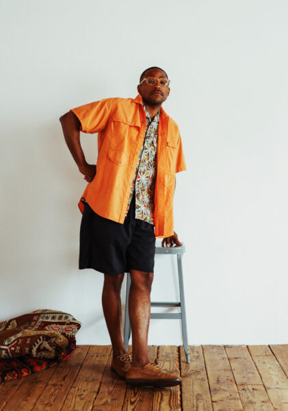 imaginea unui bărbat purtând o cămașă portocalie și pantaloni scurți negri