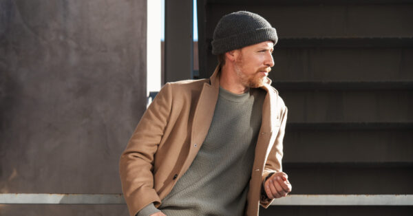 image of a man wearing a light brown coat grey shirt and black beanie hat