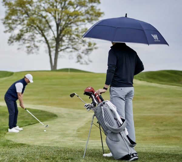 picture of a person standing on a golf course with a blue umbrella