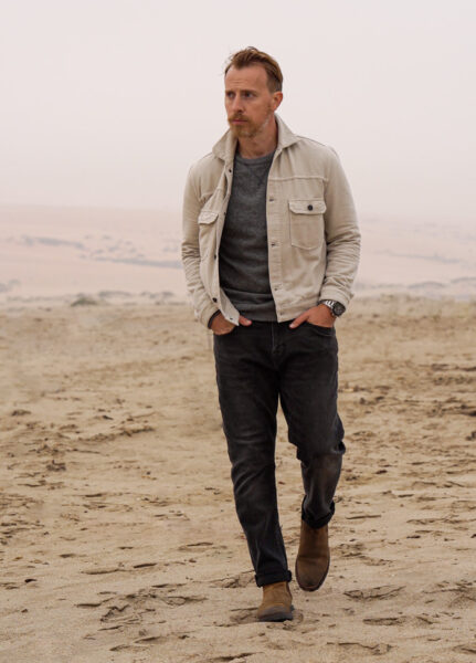 image of a man wearing a tan jacket black pants and a watch