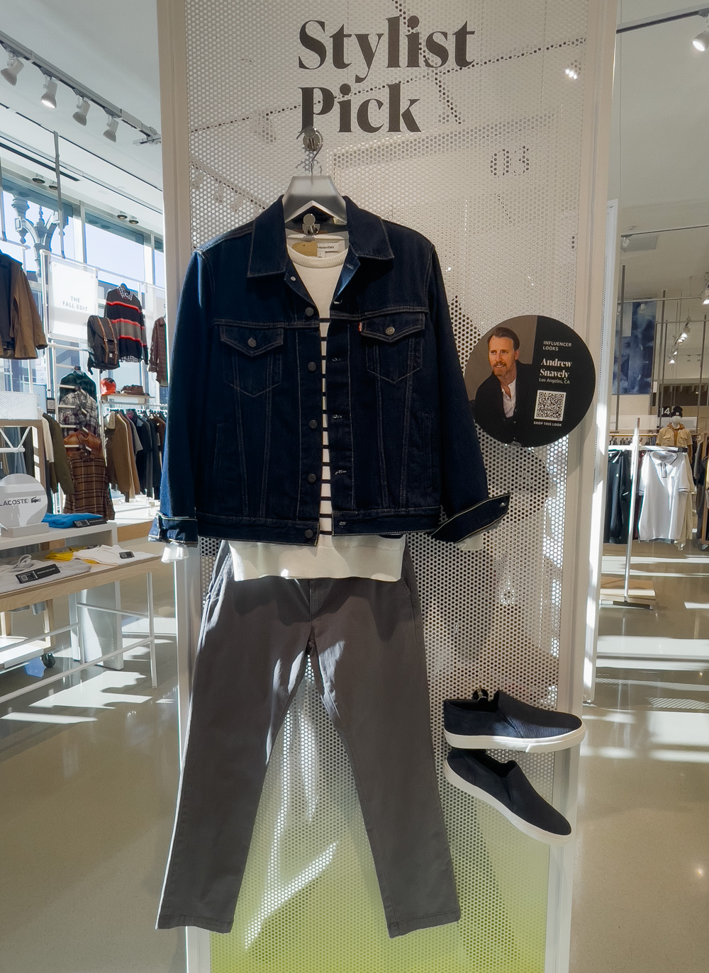 o idee de ținută lejeră expusă la magazinul în stil Amazon, cu o jachetă trucker, pulover cu dungi, pantaloni chino și pantofi sport de piele de căprioară
