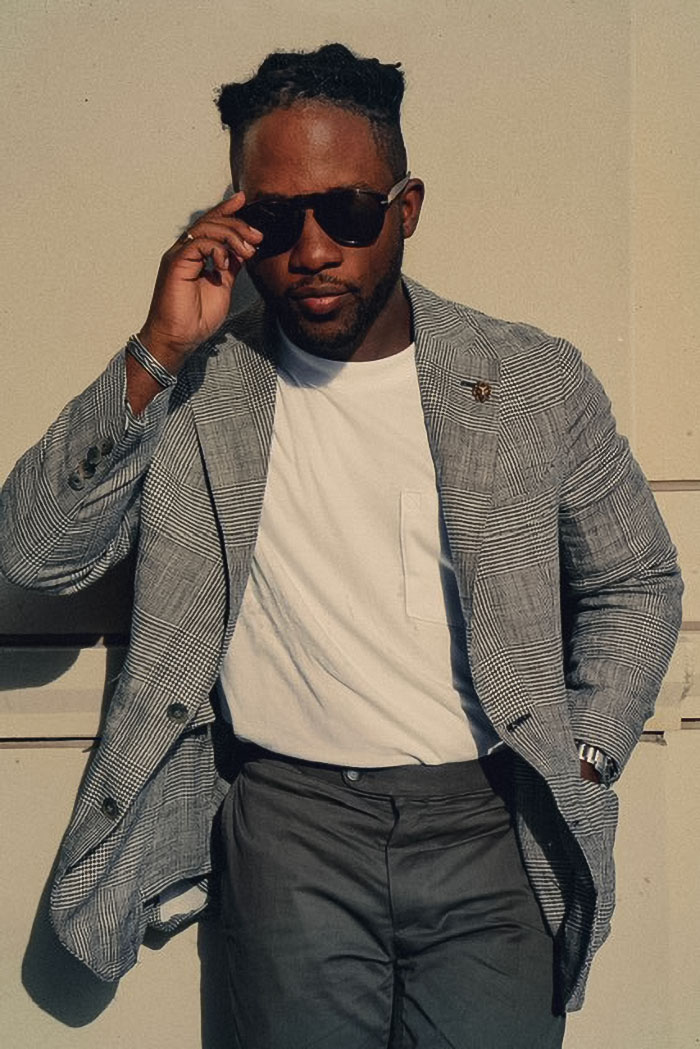 man wearing a summer outfit with linen blazer, white t-shirt, and gray chinos