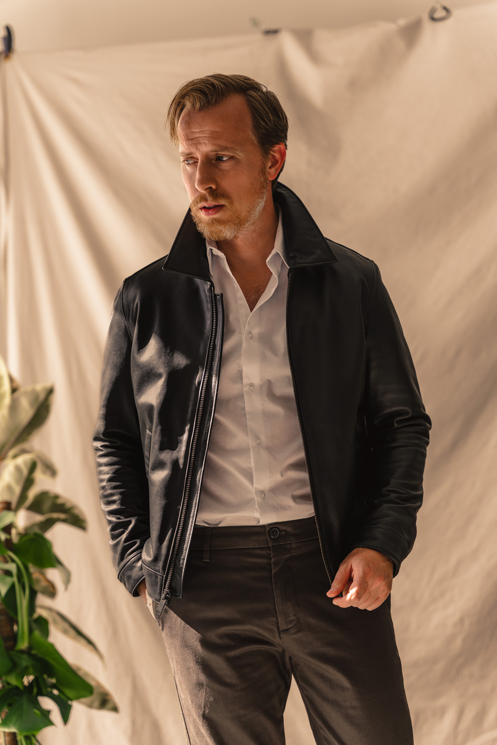 men's black leather jacket outfit inspiration with white dress shirt and brown chinos