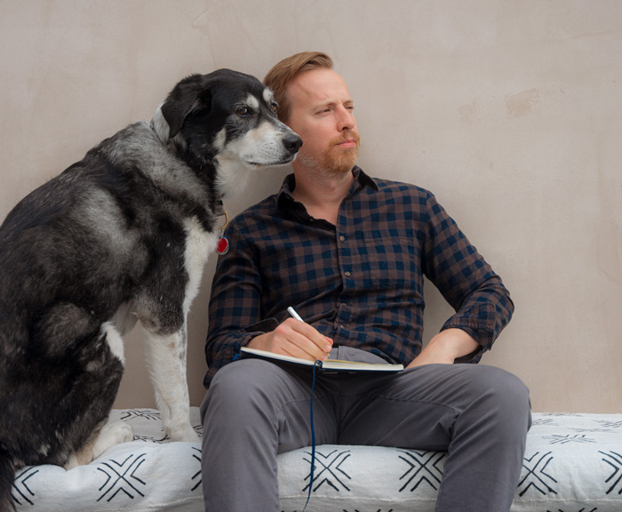 a man writing in a journal practising niksen and sitting next to a dog