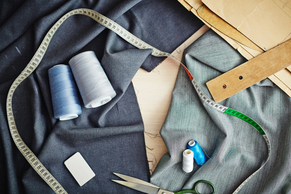 tailor tape, thread, suit pants, and chalk on table