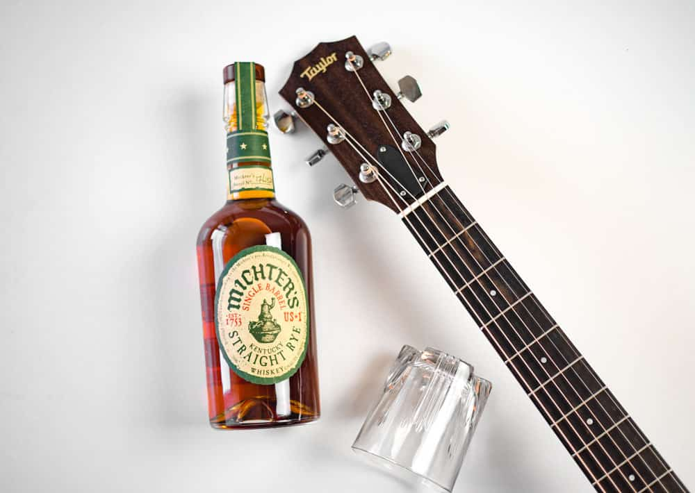 a bottle of michter straight rye whiskey and a cocktail glass next to an acoustic guitar