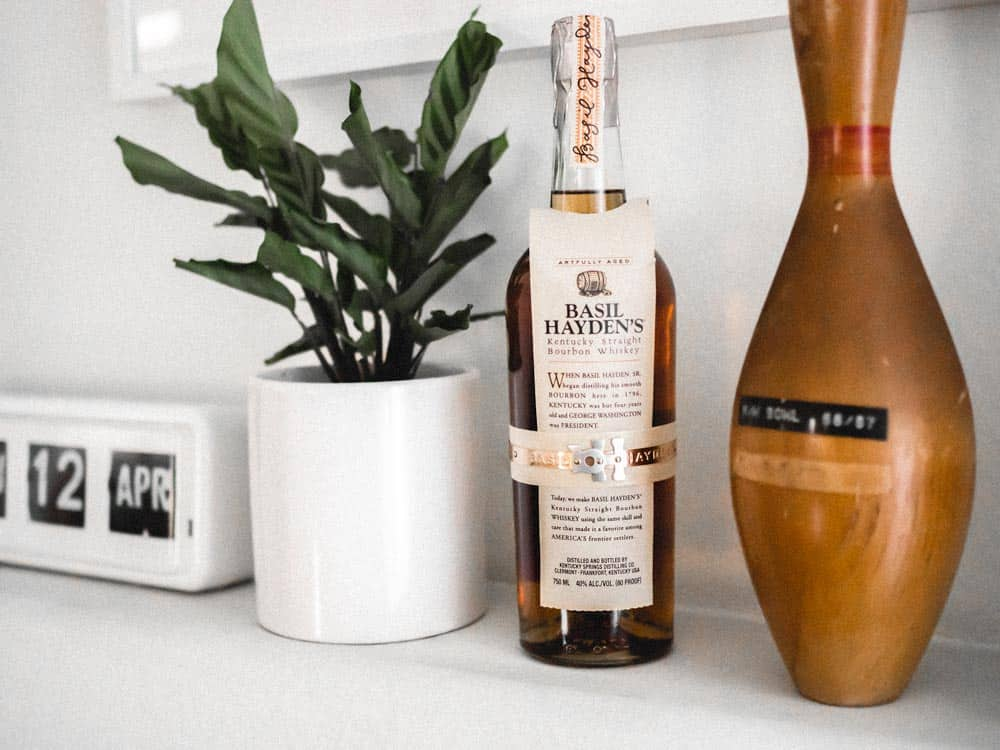 basil hayden's bourbon whiskey bottle next to bowling pin
