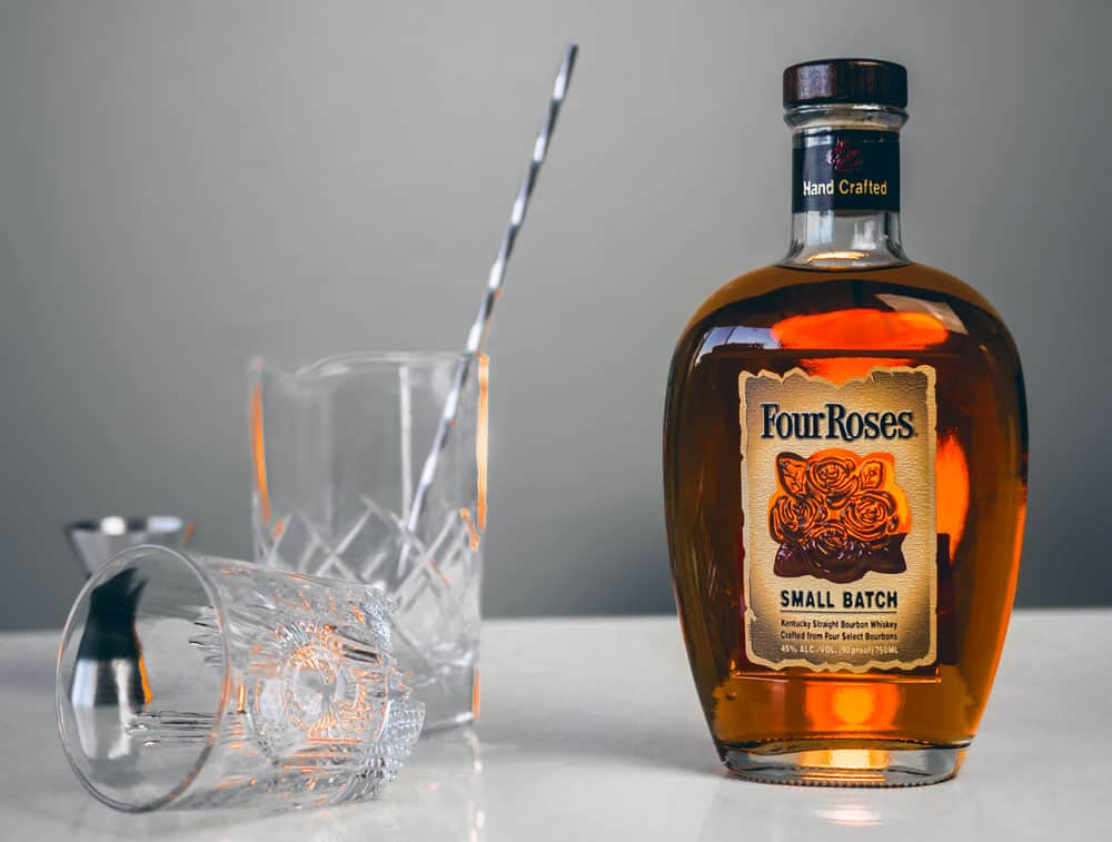 four roses small batch whiskey next to empty glasses