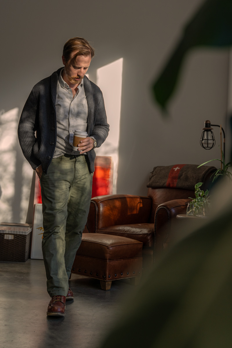 man wearing a shawl collar sweater with a button down and olive officer chinos