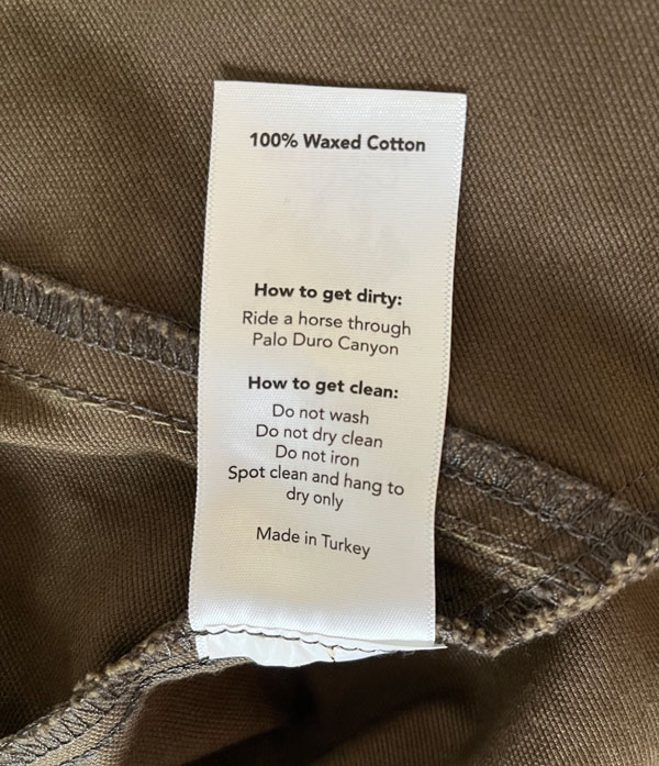 etiqueta de cuidado en la chaqueta encerada que dice que no se puede lavar y solo se limpian las manchas