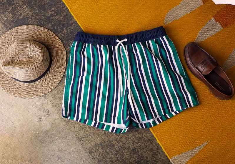 striped amazon essentials swim trunks next to straw hat and penny loafers