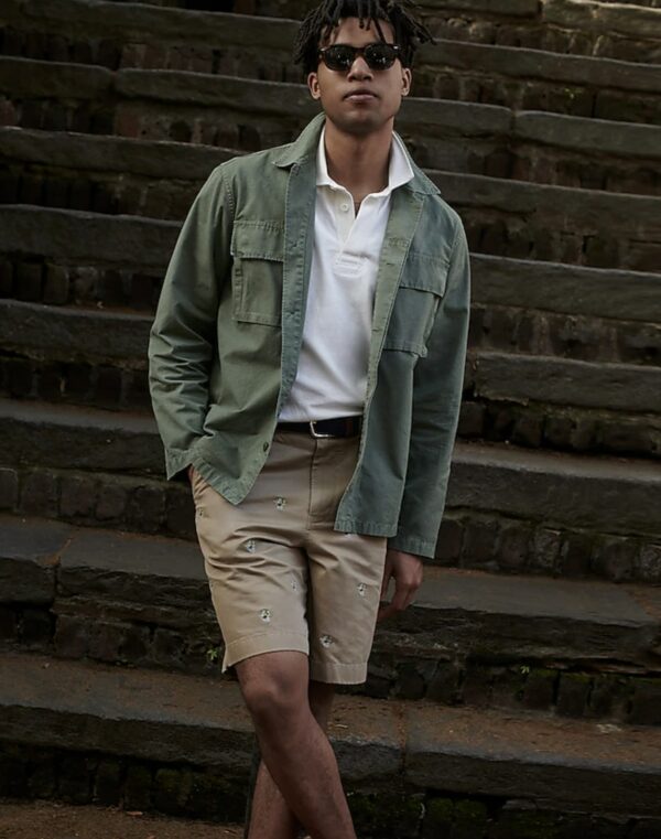 a man wearing an overshirt over a white button front shirt and shorts