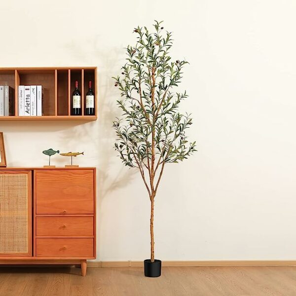 an artificial olive tree next to a drawer table