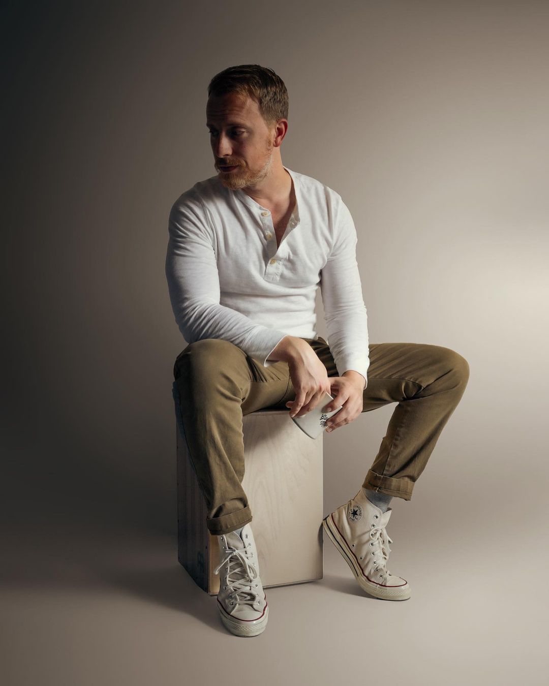 a man wearing khaki pants with a white henley and casual shoes