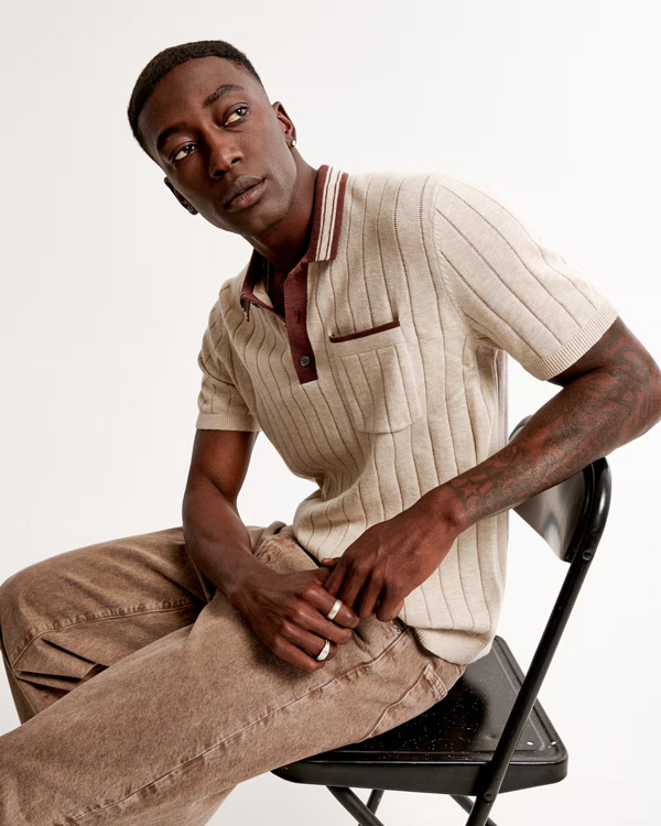 man wearing a ribbed beige polo with red accent collar and pocket detail