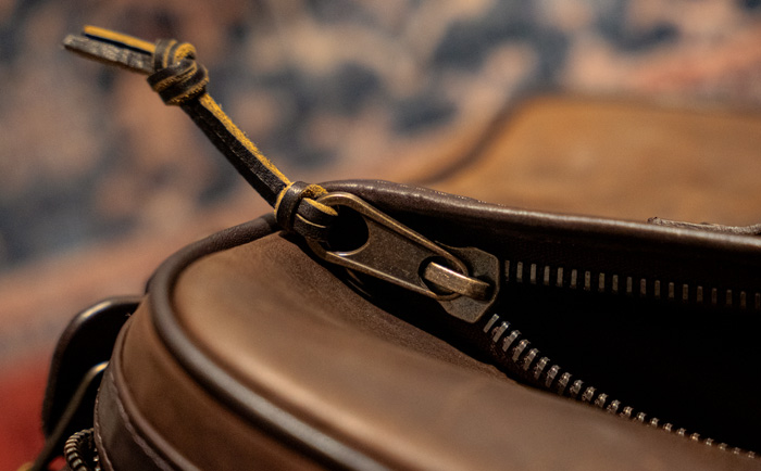 close up of a hearty brass zipper with leather pull