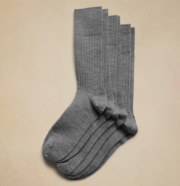 3 pairs of grey dress socks on a beige background