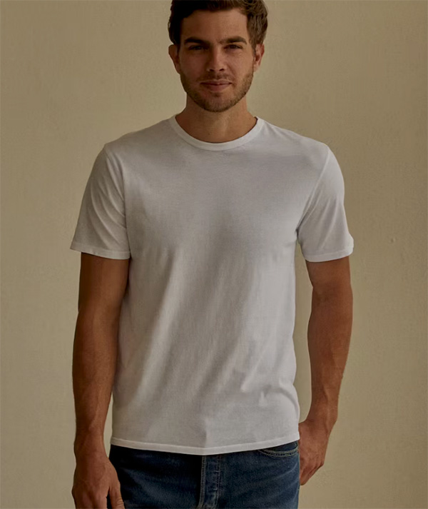 man wearing a plain white t-shirt in front of a tan background