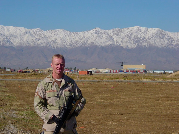 brad borland wearing a uniform standing in front snow capped mountains in afghanistan