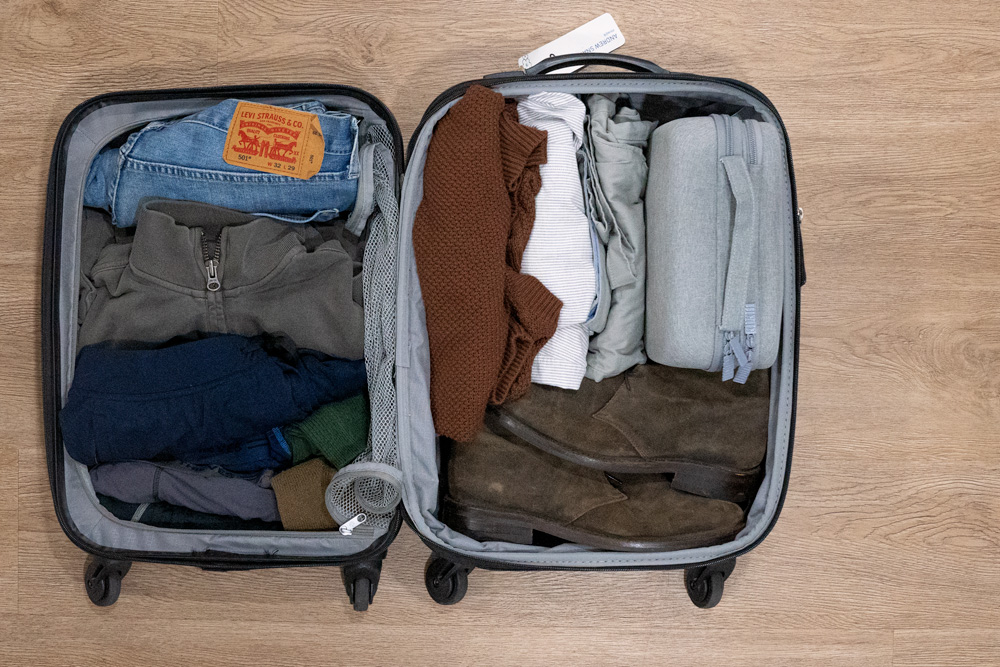 a carryon suitcase full of clothes with the hard sided dopp kit inside showing how its small, comparitively