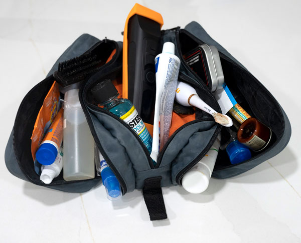 a soft sided dopp kit with toiletry items overflowing from it