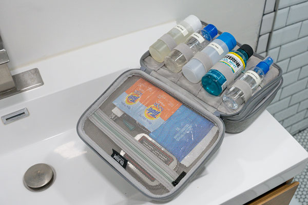 an open hard-sided toiletries travel kit sitting on the edge of a hotel sink