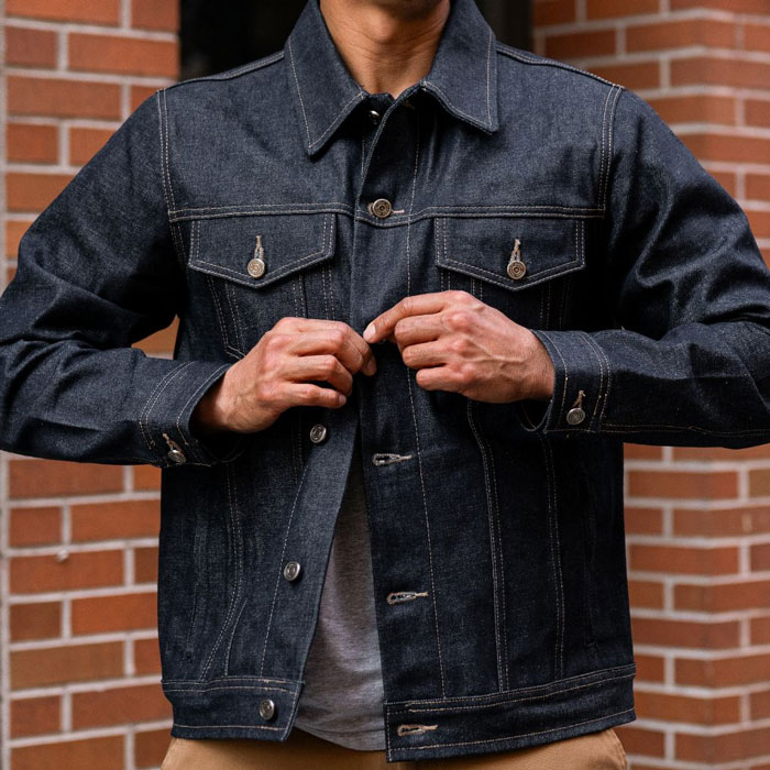 man buttoning a dark blue selvedge denim jacket