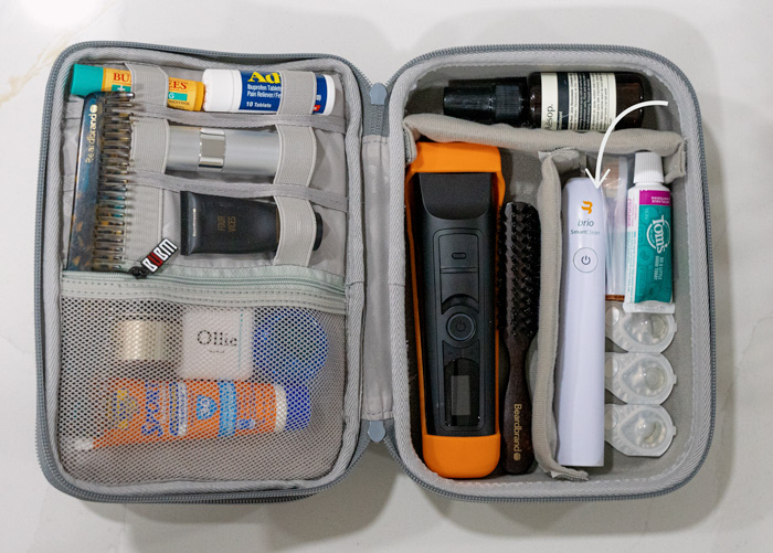 The interior of a packed toiletry kit neatly organized with an arrow pointing to an electric toothbrush