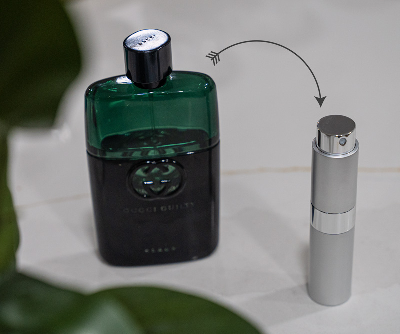 a gucci cologne bottle with an arrow pointing to a silver refillable fragrance atomizer