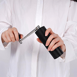 a person holding a manual coffee grinder
