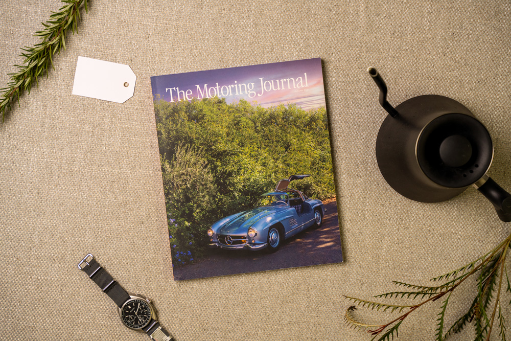 an issues of motoring journal next to a watch and kettle