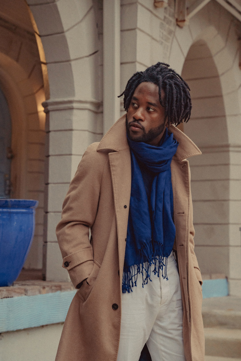 man wearing a blue scarf featuring the once around scarf, which features a loop and too ends resting in the front.