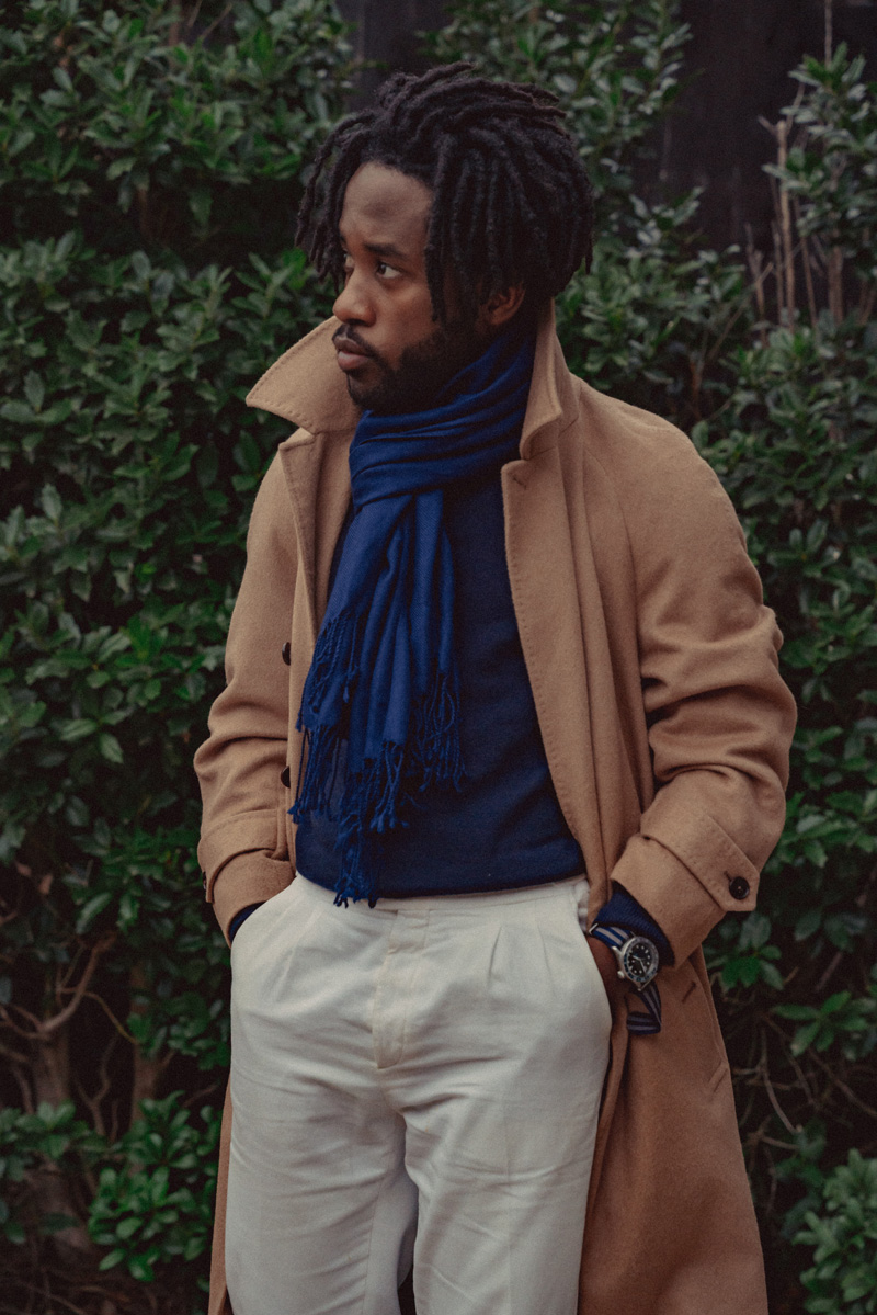 a man wearing a minimalist outfit featuring a blue scarf tied with the parsian scarf knot