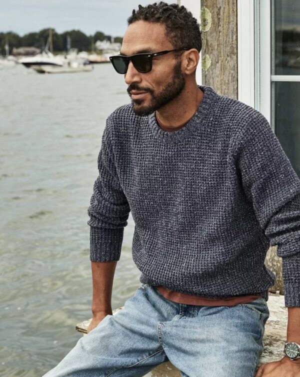 a man wearing a cotton crewneck sweater with denim jeans and accessoriezed with sunglasses