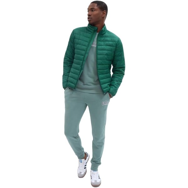 a man wearing a puffer jacket over a sweater and sweat pants and casual sneakers
