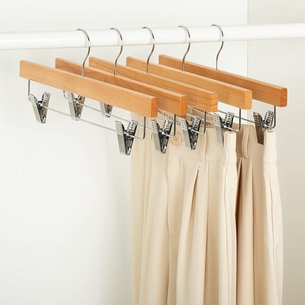 wooden pant hangers with clips hanging in a closet 