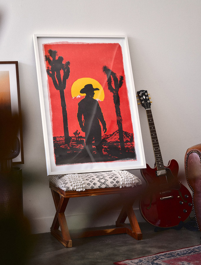 a western inspired art piece in a square frame leaning against a wall 