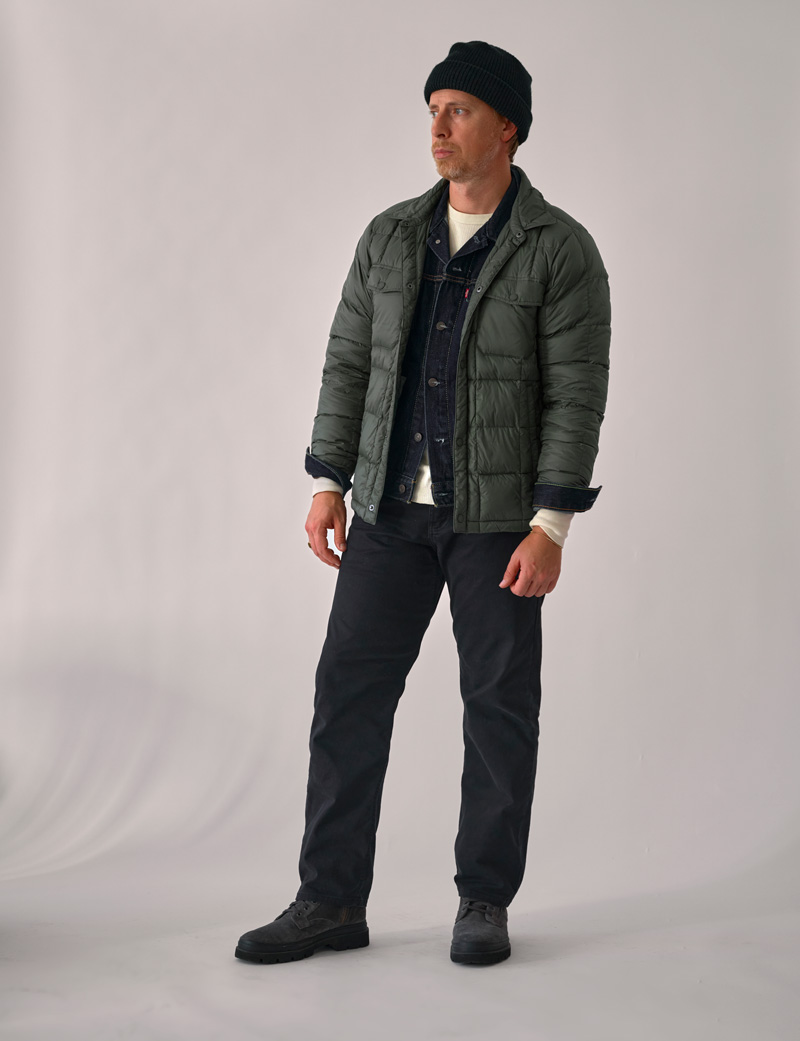 men's fall outfit idea with a green puffer over a denim jacket with black jeans and boots