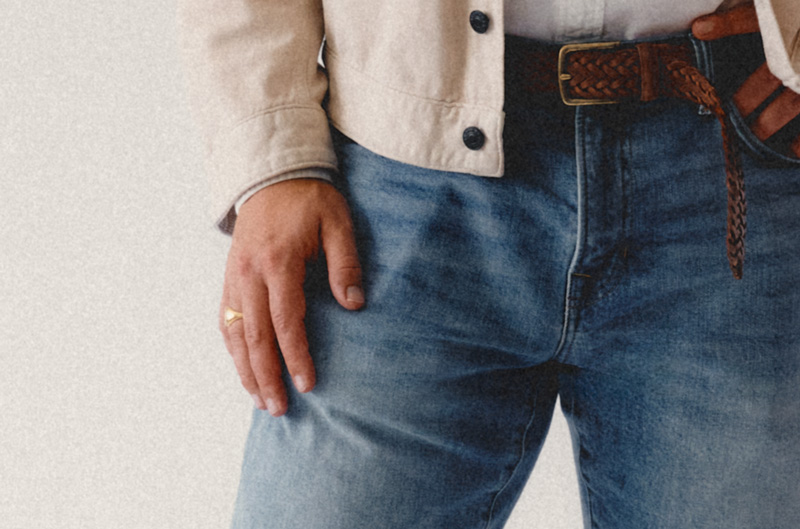 men's light wash jeans with a brown leather braided belt and a gold ring