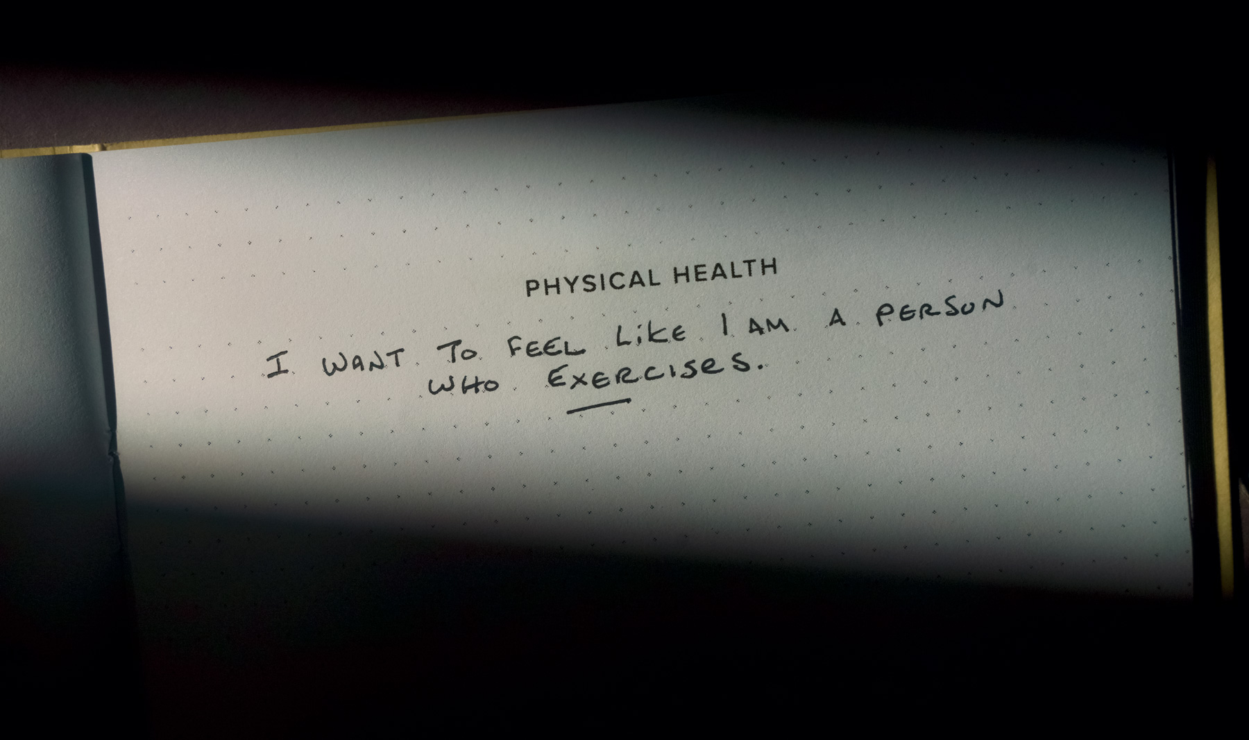 A close-up image of a notebook page with the heading 'PHYSICAL HEALTH' and the handwritten text: 'I WANT TO FEEL LIKE I AM A PERSON WHO EXERCISES.'