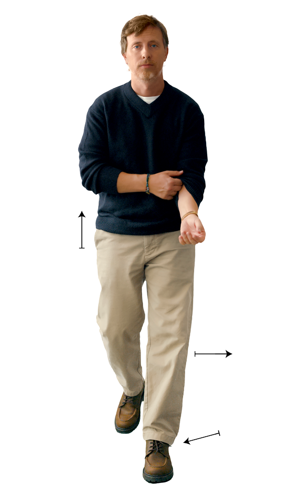 Man in a navy v-neck and khaki chinos worn at the natural waist, with arrows marking the rise and the half break over a moc toe boot