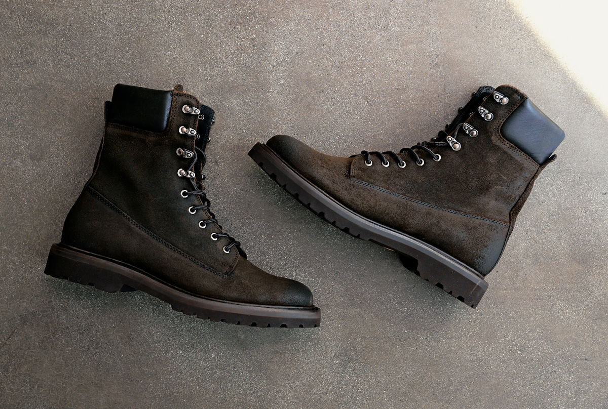 Pair of Thursday Explorer combat boots in Dark Olive suede on a concrete floor