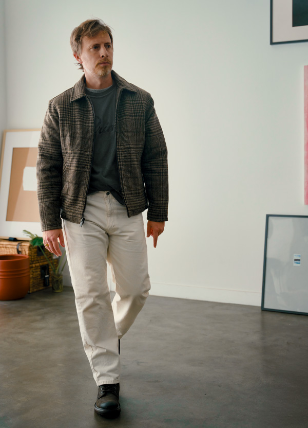 Thursday Station Jacket in Elmwood worn over a graphic tee with off-white jeans and dark olive boots